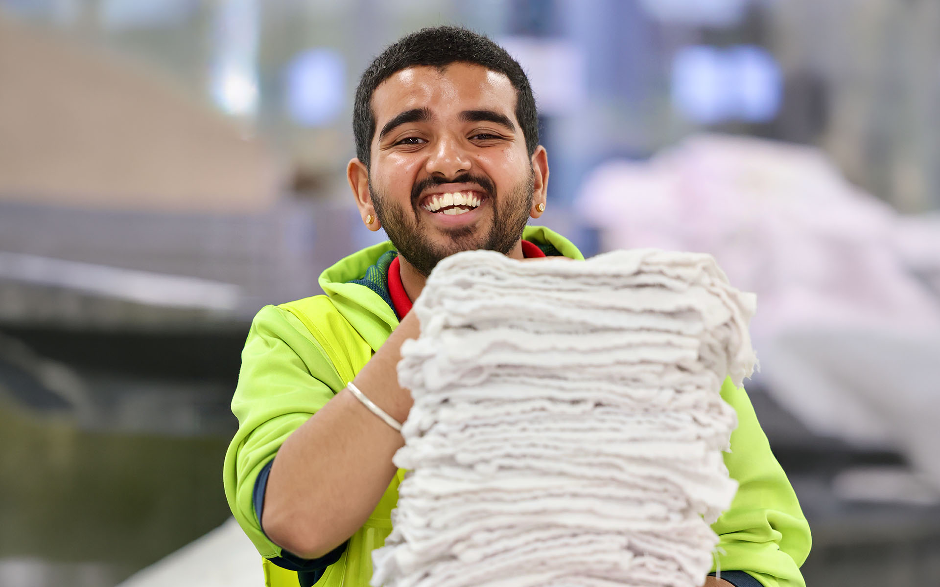 A Wallara participant holding folded linen in a workplace environment.