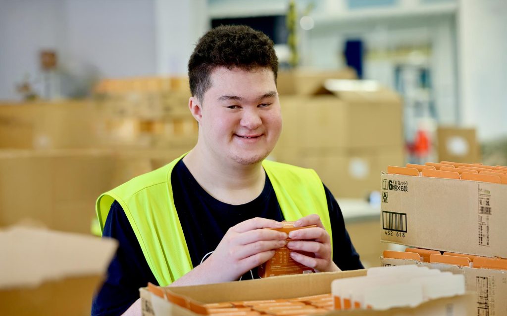 A Wallara participant sorting items in a warehouse workspace.