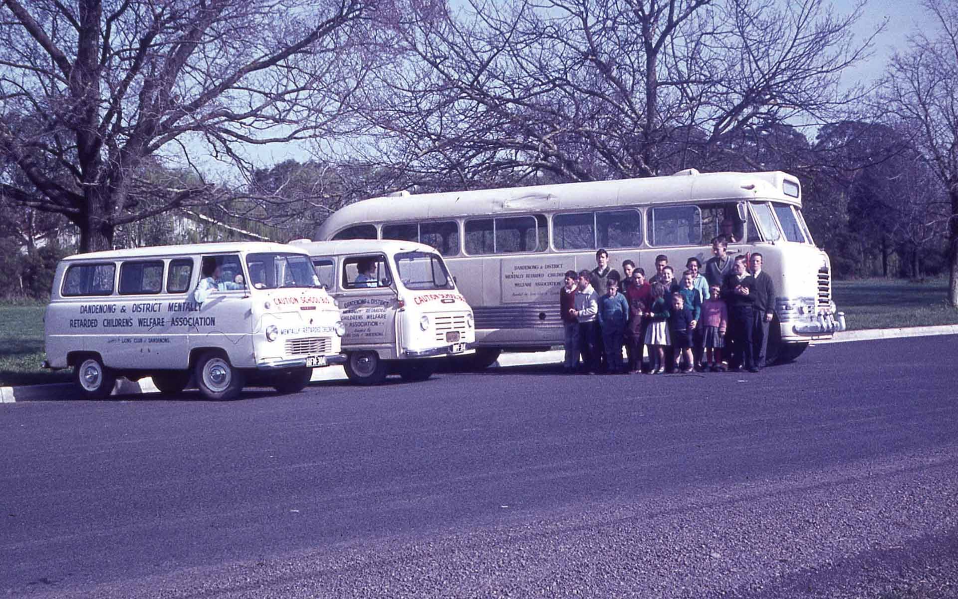 Wallara participants and staff standing beside buses during a community outing.