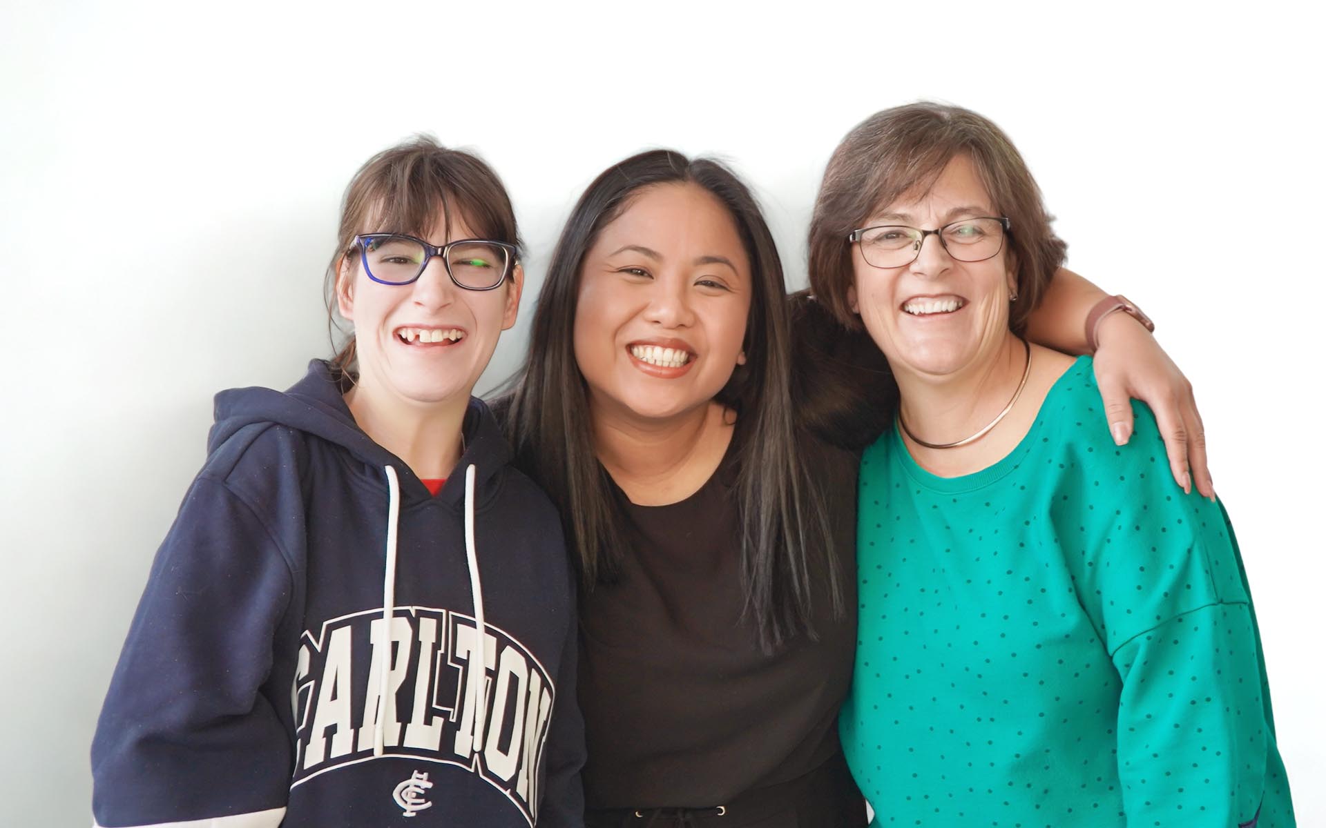 Two Wallara team members and a Wallara participant stand together with their arms around each other, smiling at the camera.